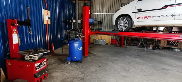 CASAMOTO tire equipment and air compressor beside a vehicle on a lift