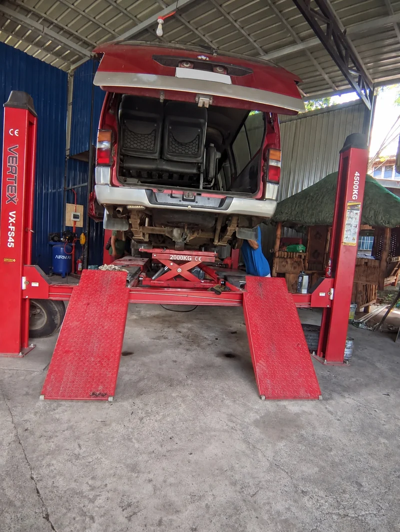 Rear of a van raised above a red service lift with its tailgate open
