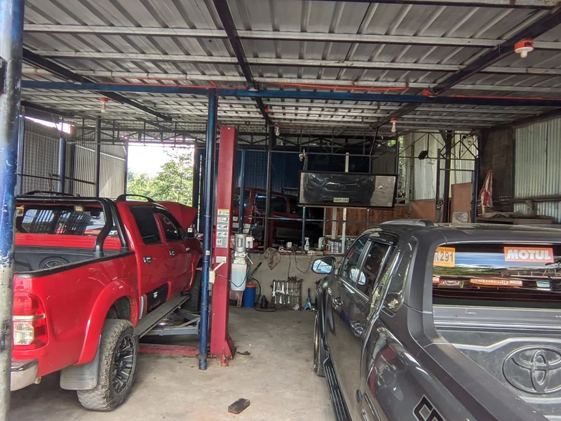 CASAMOTO workshop with red and dark pickups beside a service lift